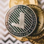 Deux mains tiennent des pièces de crypto sur fond d'écran de trading