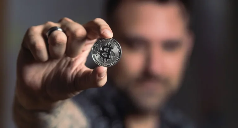 Gros plan sur deux mains tenant une clé USB devant un écran crypto