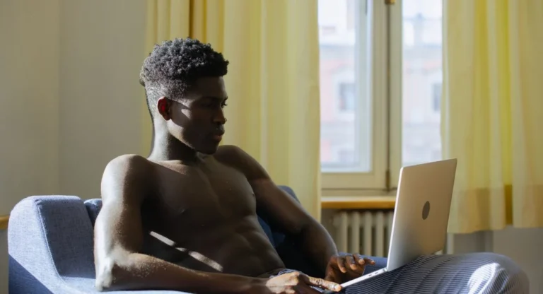 Jeune adulte devant ordinateur cherchant Coflix dans un salon éclairé, air concentré