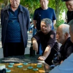Joueurs devant une table, tuiles de jeu façon chaînes reliées, ambiance studieuse