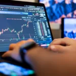 Trois personnes analysent des écrans de trading dans une salle remplie d'ordinateurs