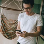Un jeune homme consulte son wallet crypto sur smartphone dans un café moderne