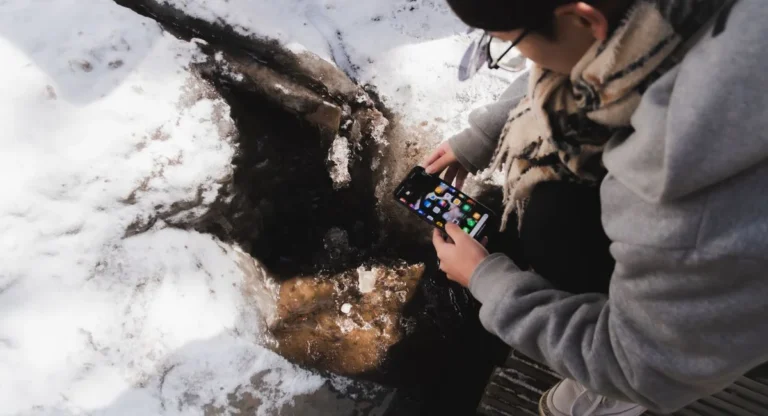 Utilisateur pointant son smartphone vers un objet réel avec superposition d'informations numériques en réalité augmentée