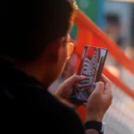 Utilisateur tenant un smartphone affichant des objets virtuels en 3D superposés à un bureau réel