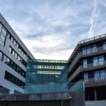 Vue dynamique du nouveau bâtiment UDRIZ au soleil, façades vitrées et visiteurs