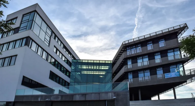 Vue dynamique du nouveau bâtiment UDRIZ au soleil, façades vitrées et visiteurs