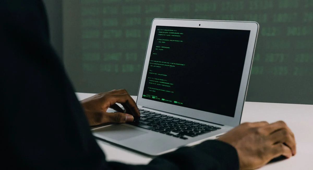 A focused adult working on a laptop demonstrates modern cybersecurity and coding skills indoors.